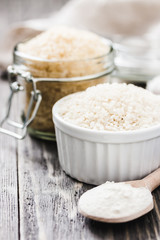 Two kinds of rice grains and flour in glass jars on wooden rustic background. Selective focus, space for text.