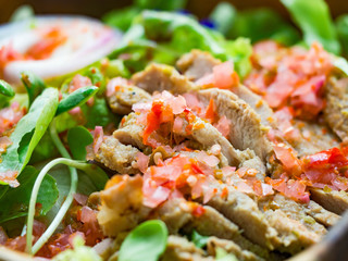 Grill pork slice mixed with vegetable, chili, lemon in wood bowl on wood table