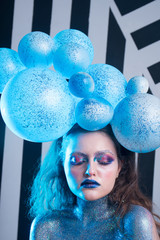 Young attractive girl in makeup, in glasses and balloons on the head	