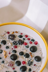 Vertical close-up of cereal porridge and fruits bowl on tablecloth.