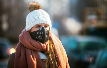 Young woman wearing protective mask in the city street, smog and air pollution