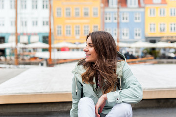 Happy young tourist woman  at the Nyhavn harbor pier Copenhagen, Denmark. Visiting Scandinavia, famous European destination during fall or spring.