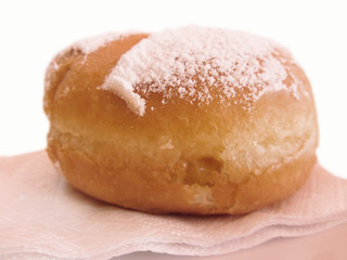 Single Krapfen ( italian doughnut ) covered with icing sugar on napkin isolated on white background