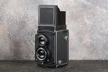 The old medium-format TLR camera on cement wall background.