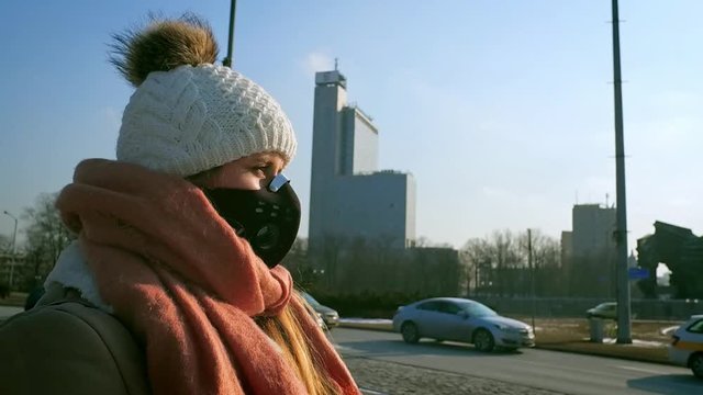 Woman wearing protective mask in the city street, smog and air pollution at winter
