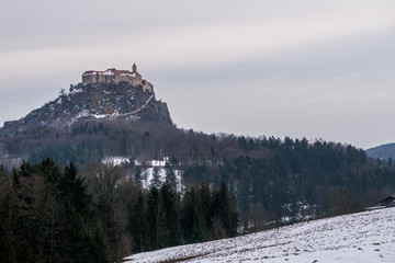 A snow covered field in the foreground with the beautiful Riegersburg castle in the background