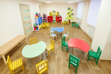 Spacious light pink colored game room with tables for classes in the kindergarten