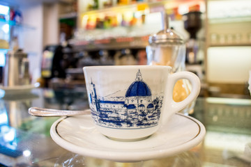 Florence, Tuscany/Italy - March 3, 2018. coffee shop on the bar is a white small Cup of espresso coffee. on the Cup painted symbol of Florence Cathedral of Santa Maria del Fiore.