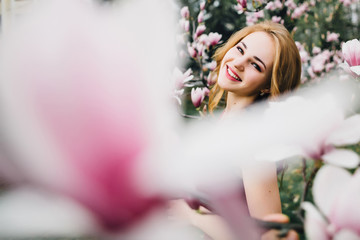 Beautiful girl in the flowering cherry blossom. In a burgundy dress with beautiful hair and makeup