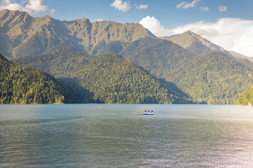 Fototapeta na wymiar Ritsa lake in the mountains and a catamaran