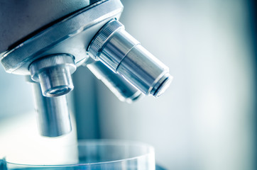 Close-up shot of microscope with metal lens at laboratory. Scientific and healthcare research background.