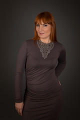 Attractive woman posing in studio: model with red or ginger hair wearing slinky dress