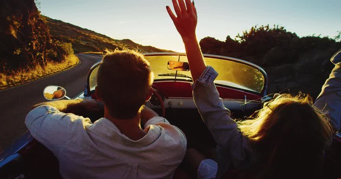 Driving into the sunset, romantic couple enjoying beautiful drive on country road