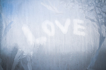 Love inscription on the frozen window in winter patterns in winter