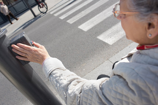 elderly woman pressing crosswalk button