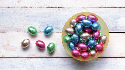 Some easter eggs in a bowl on a white wooden table. Empty copy space for Editor's text. Top view