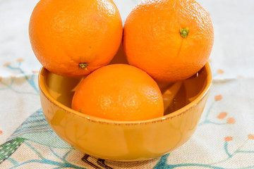 Three oranges in yellow bowl 