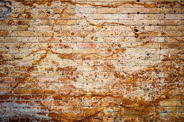 Background wall from an ancient yellow vintage brick with rusty corrosion patterns on the surface. Textured background in grunge style. Procurement for stylish graffiti