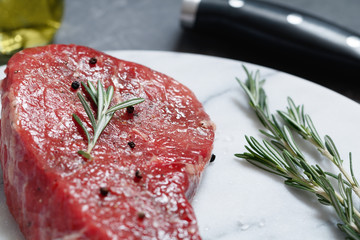 Raw beef steak on a white marble salver. The process of preparation dinner.