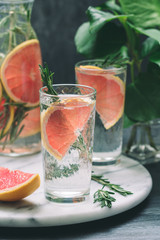 Cold cocktails with grapefruit and rosemary on a white marble serving tray.