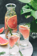 Cold cocktails with grapefruit and rosemary on a white marble serving tray.