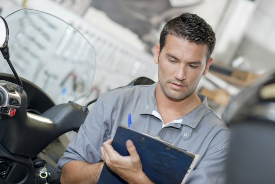 Mechanic making notes on clipboard