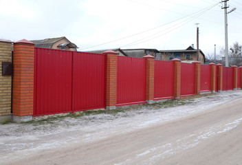 Obraz premium Long metal fence with entrance gate on the suburban street side