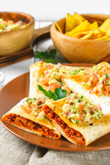 Traditional Mexican dish - chimichanga. Corn cake with minced meat, pepper, onion, garlic, oregano, zira and guacomole sauce from avocado.