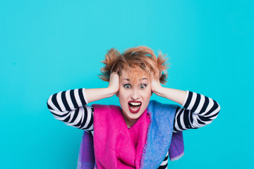 Girl with red hair holding her head shouting. Stress and hysterical. negative emotions. Studio shot. Blue  background