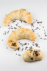 drei gebackene Frühstücks Schokoladen Croissants Hörnchen mit Schokoladenstreuseln vor weißem Hintergrund