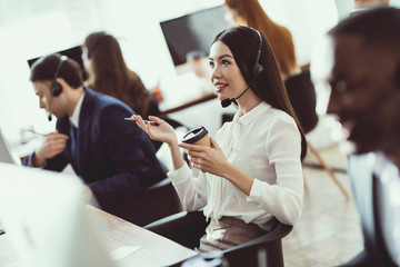 The Asian girl answers questions from clients in the call center.