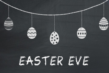 Easter eggs on a black chalkboard with text Happy eve