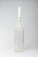 london, england, 05/05/2017, A clear glass bottle with melted dripping candle dripping down the bottle. The white clean candle is new and unlit.