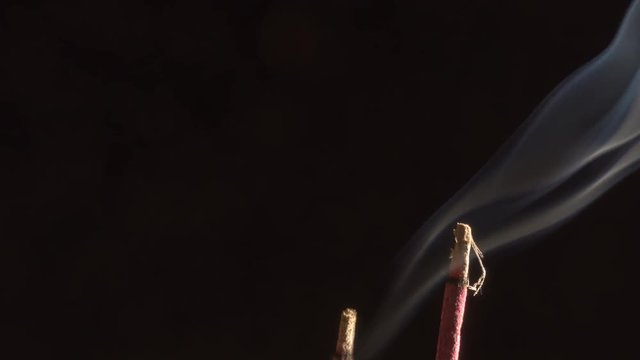 Smoke of incense sticks over black background. Copyspace composition