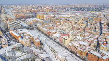 Aerial view of the Tuscolana station in Rome, Italy. Around the tracks there are the palaces and streets of the Italian city. The railroad tracks are made of steel. Everything is covered by snow on 02