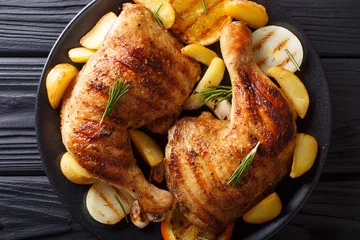 Foto op Plexiglas anti-reflex grilled chicken leg with oranges, onions and potatoes macro. Horizontal top view © FomaA