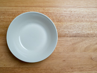Empty porcelain bowl on wooden chopping block