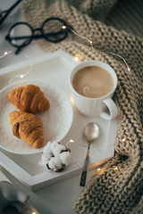Cozy home breakfast, warm blanket, coffee and croissant on white