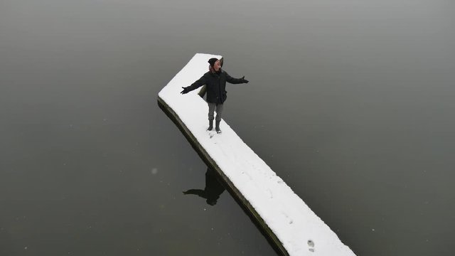 Ragazzo felice sul molo del lago in inverno