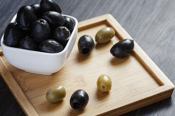 Olives in a white bowl on a dark wooden table