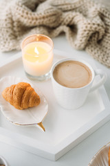 Cozy home breakfast, warm blanket, coffee and croissant on white