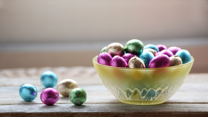Some easter eggs in a bowl on a white wooden table. Empty copy space for Editor's text.