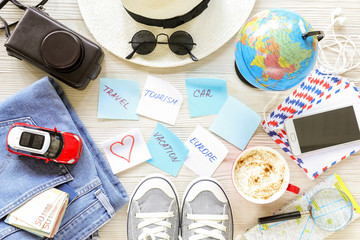 Traveler's accessories and items, stickers with notes on white wooden background, planning travel to Europe by car concept.