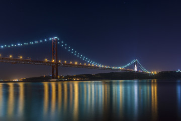 Obraz premium Beautiful and serene view of the Tagus River and the 25 of April Bridge (Ponte 25 de Abril) at night, in Lisbon, Portugal; Concept for visit Lisbon