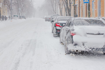 A snow covered car drives in winter storm