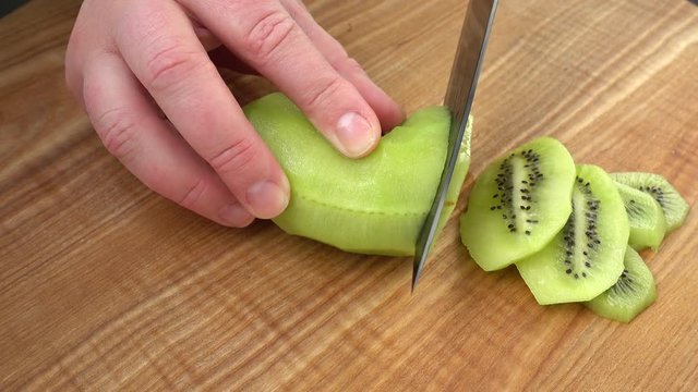 	The cook cuts pieces of a kiwi.	Cooking shooting.	