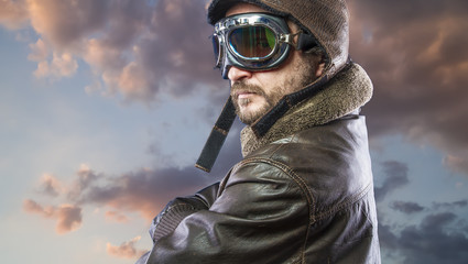 Fototapeta premium Proud, pilot of the 20s with sunglasses and vintage aviator helmet. Wears leather jacket, beard and expressive faces