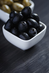 Olives in a white bowl on a dark wooden table