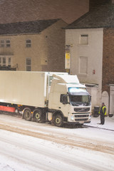 lorry stuck in traffic in snow with buildings in background UK