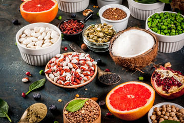 Set of organic healthy diet food, superfoods - beans, legumes, nuts, seeds, greens, fruit and vegetables. Dark blue background copy space